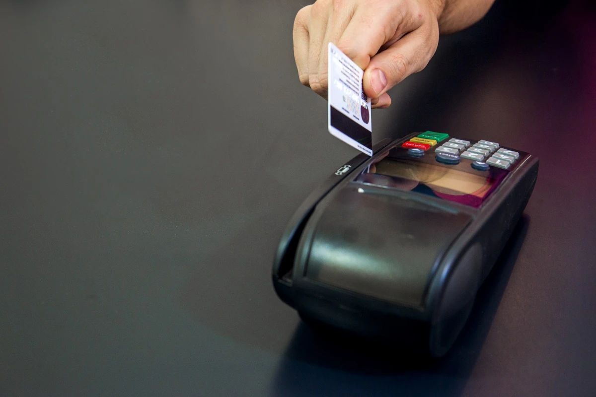 بطاقة مصرفية تلامس جهاز نقاط بيع لإتمام دفعة