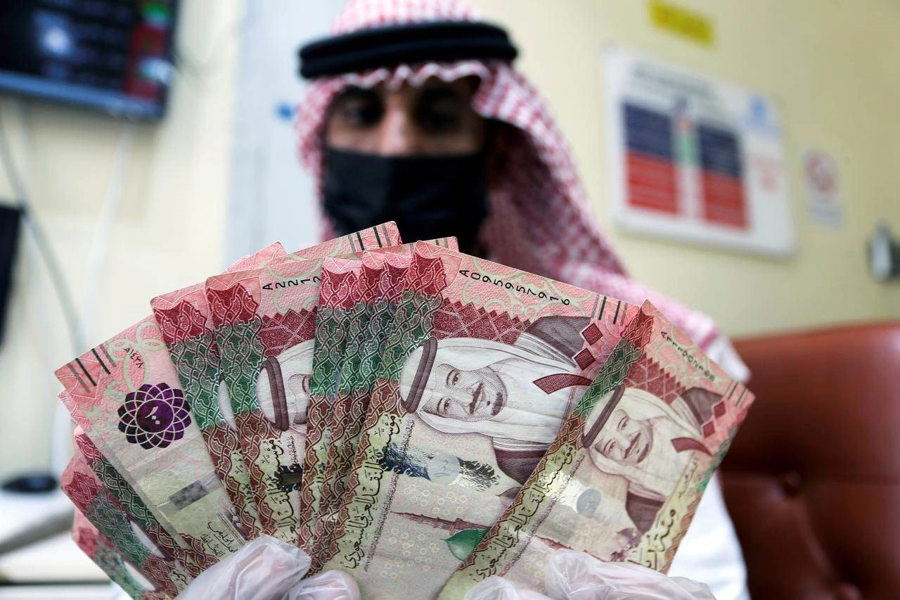 رجل سعودي يعرض أوراقًا نقدية من فئات مختلفة